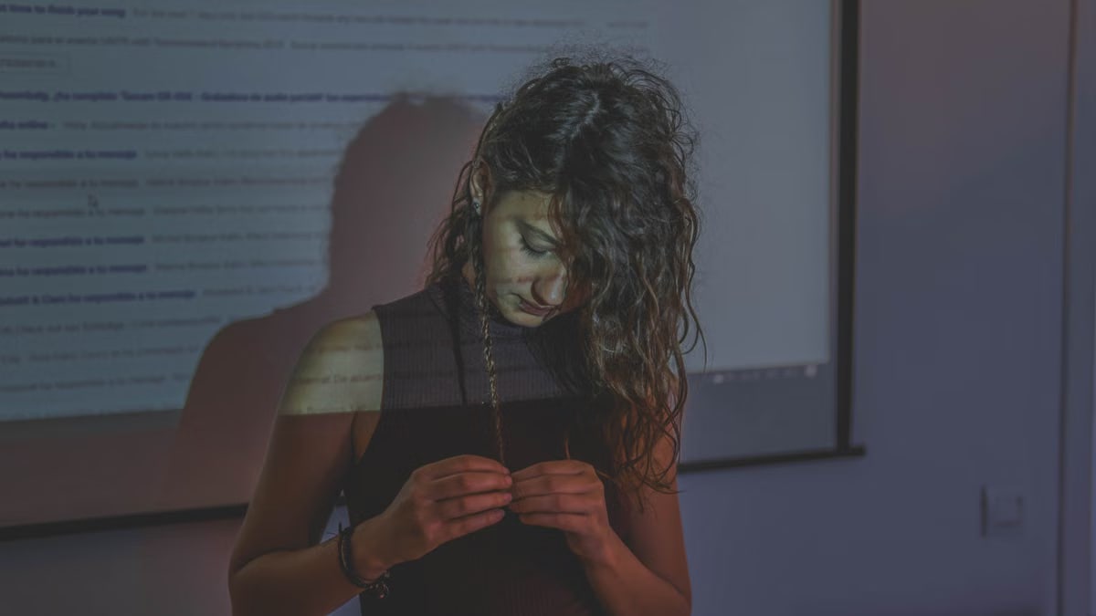 A woman standing in front of a projector screen showing complex patterns.